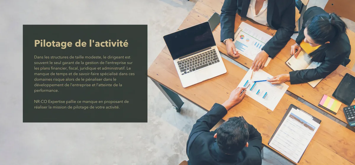 Photo d’un bureau vu de haut où sont attablés des clients de NR-CO Expertise qui demandent à Nathalie Rayon des précisions sur leurs tableaux de pilotage d’activité